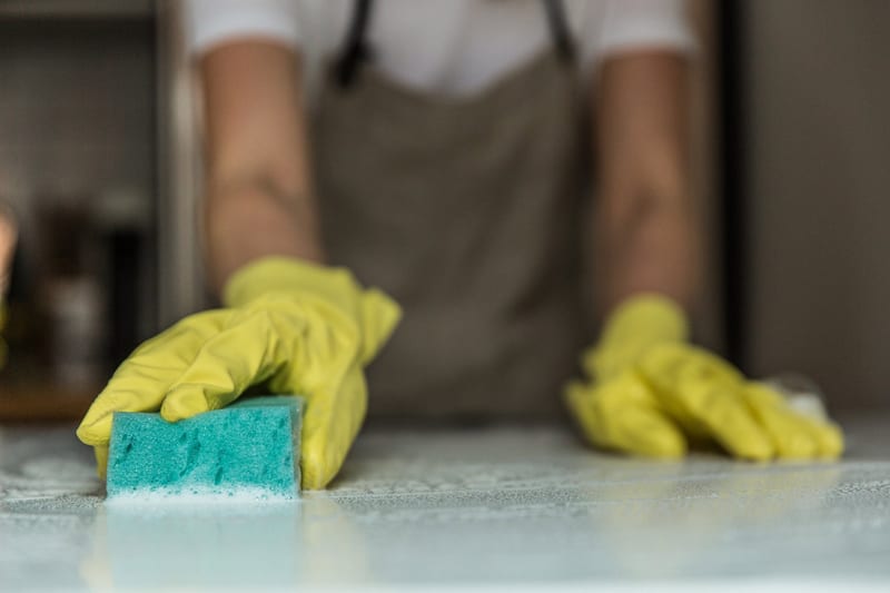 a person wearing yellow gloves is cleaning a counter with a sponge