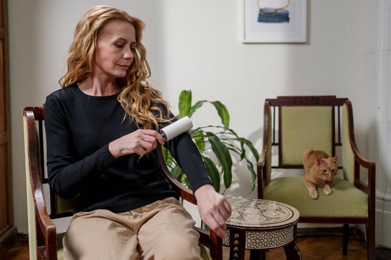 a woman is sitting in a chair cleaning her arm with a lint roller