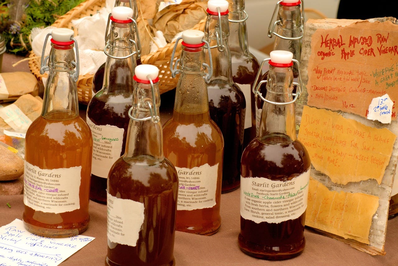 Swing-top bottles of homemade apple cider vinegar for sale at a farmers market