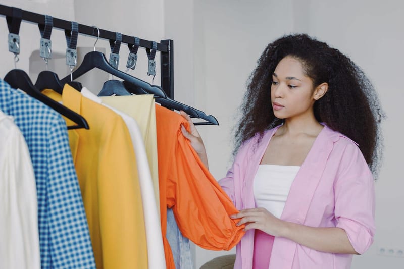a woman in a pink shirt is looking at clothes on a rack