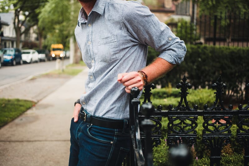a man leaning on a fence with his hands in his pockets
