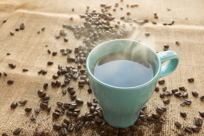 a cup of coffee is surrounded by coffee beans