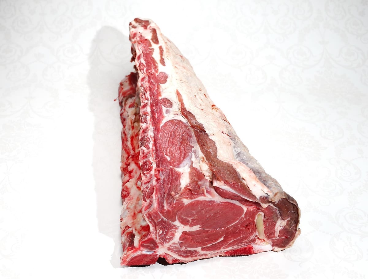A raw bone-in beef rib roast with a thick fat cap