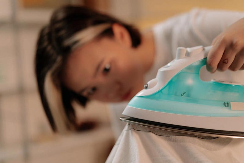 a woman is ironing a shirt with a heart tattoo on her hand