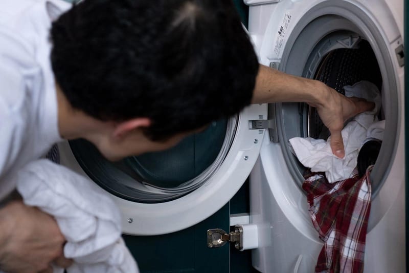 a man is putting clothes in a washing machine