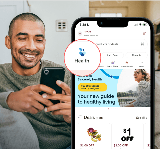 Smiling man holding a phone with the Health tab highlighted on a grocery app screen