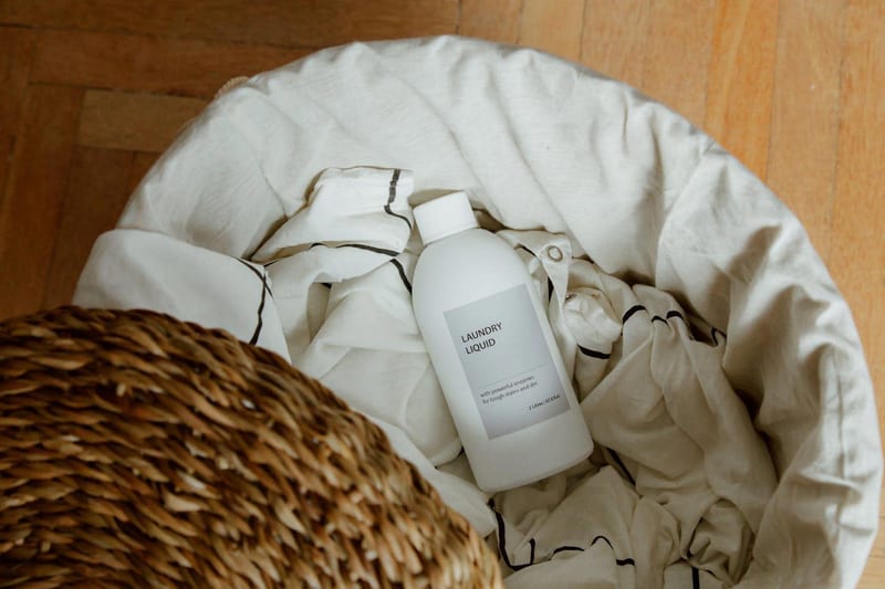 a bottle of laundry liquid sits in a laundry basket