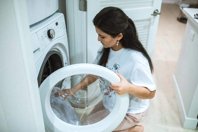a woman is kneeling down in front of a washing machine