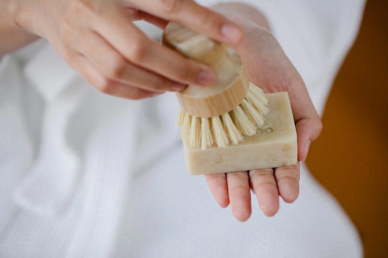 a person is holding a bar of soap and a brush in their hand