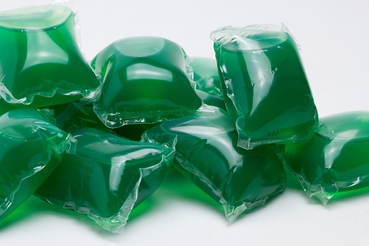 Green liquid laundry detergent pods on a white surface