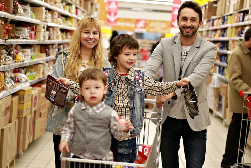 a family is shopping in a grocery store and the man is wearing a shirt that says ' ll ' on it