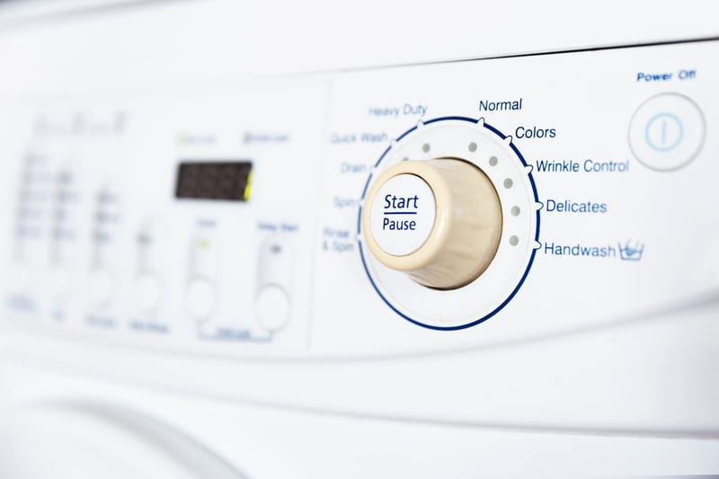 a white washing machine has a start pause button