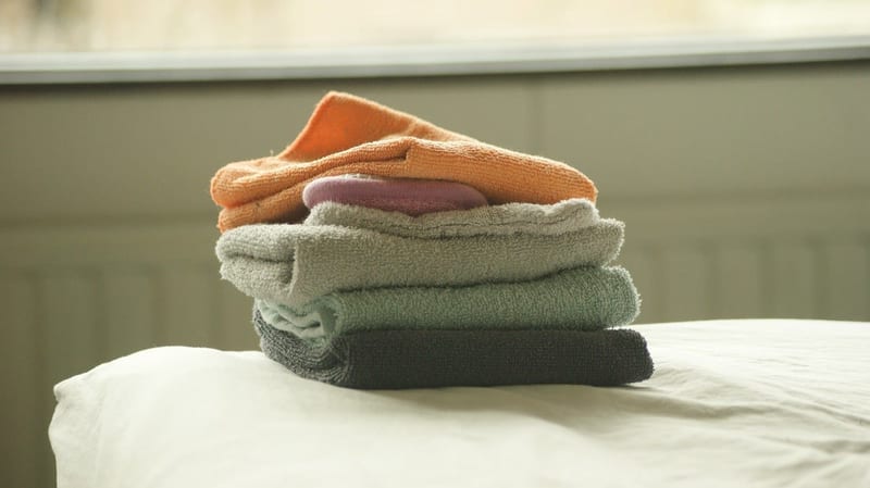 a stack of towels with a pink soap in the middle