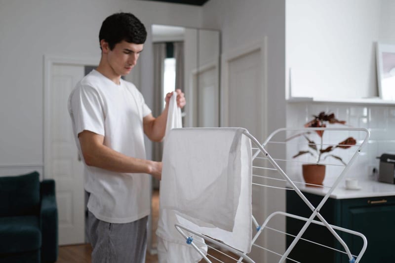 a man is hanging clothes on a drying rack in a living room