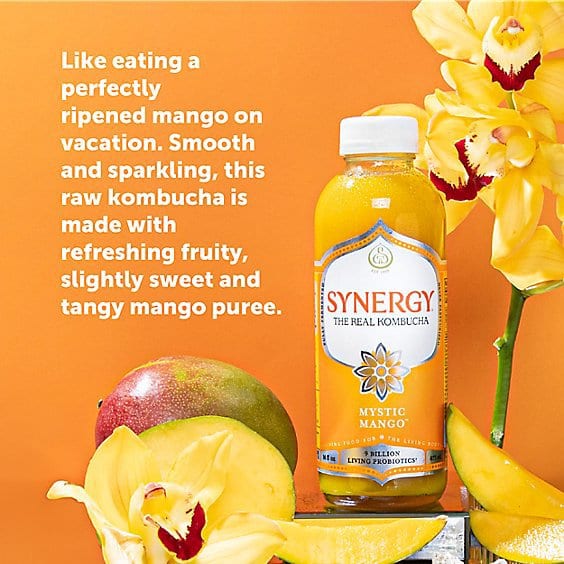 GT's Synergy Mystic Mango kombucha bottle displayed with mangoes and yellow orchids on an orange background.