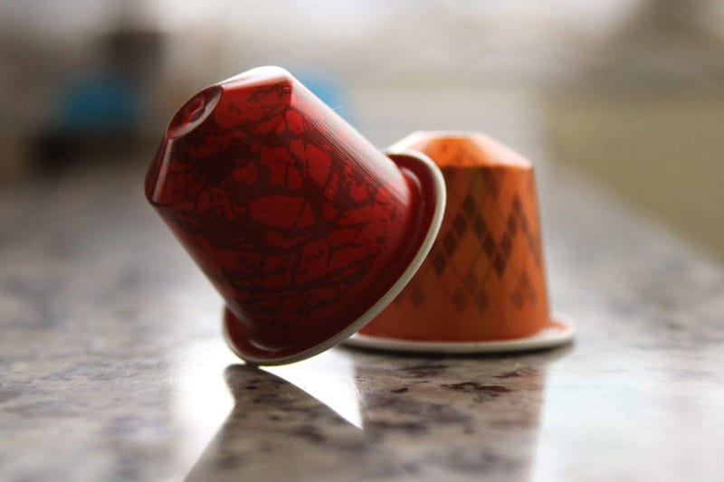 two coffee pods one red and one orange are on a counter