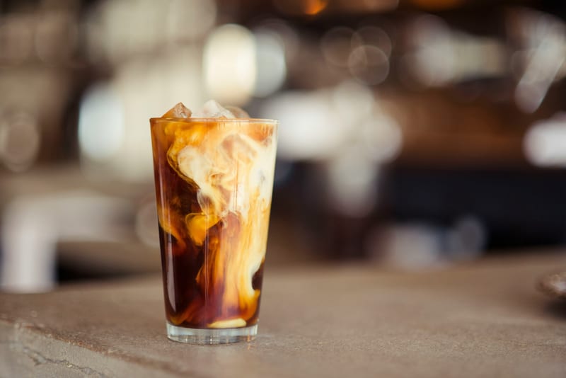 a glass of iced coffee with cream on a counter top