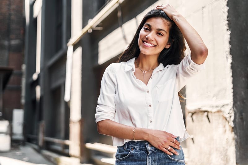 a woman wearing a white shirt and blue jeans is smiling