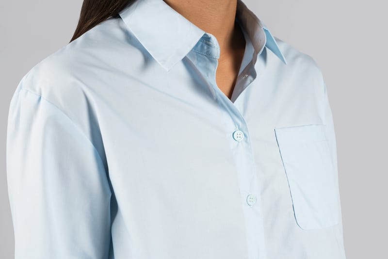 a woman is wearing a light blue shirt with buttons