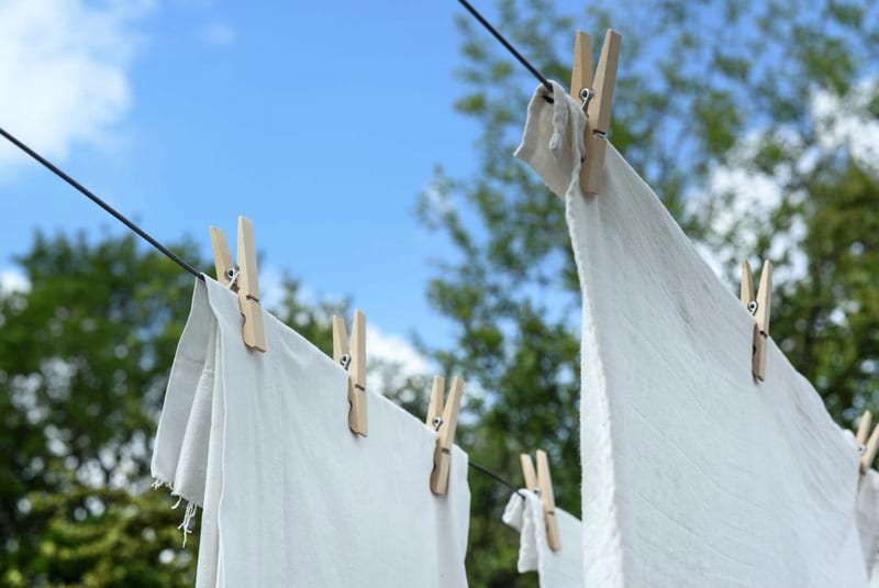 white clothes are hanging on a clothes line with wooden pegs