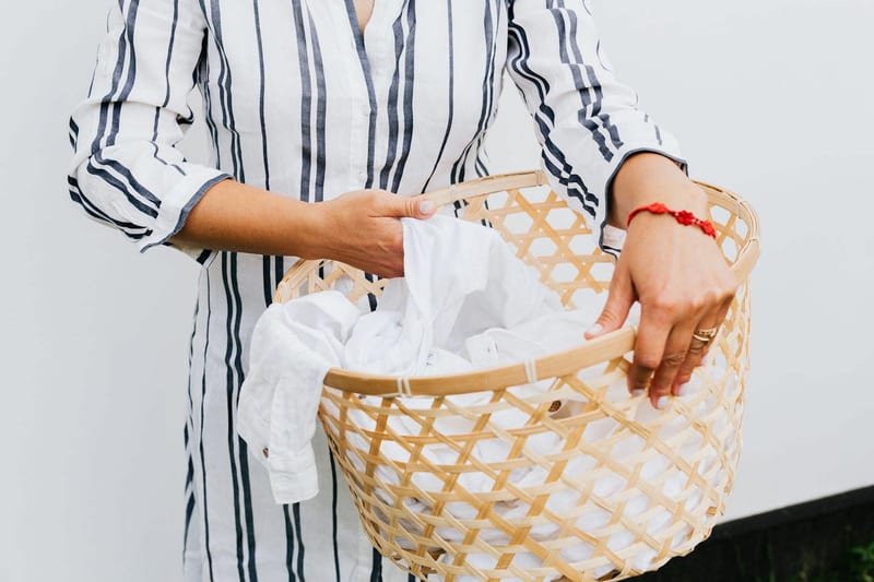 a woman is holding a laundry basket filled with white clothes