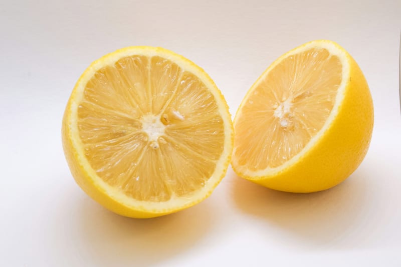 two lemons are cut in half on a white surface