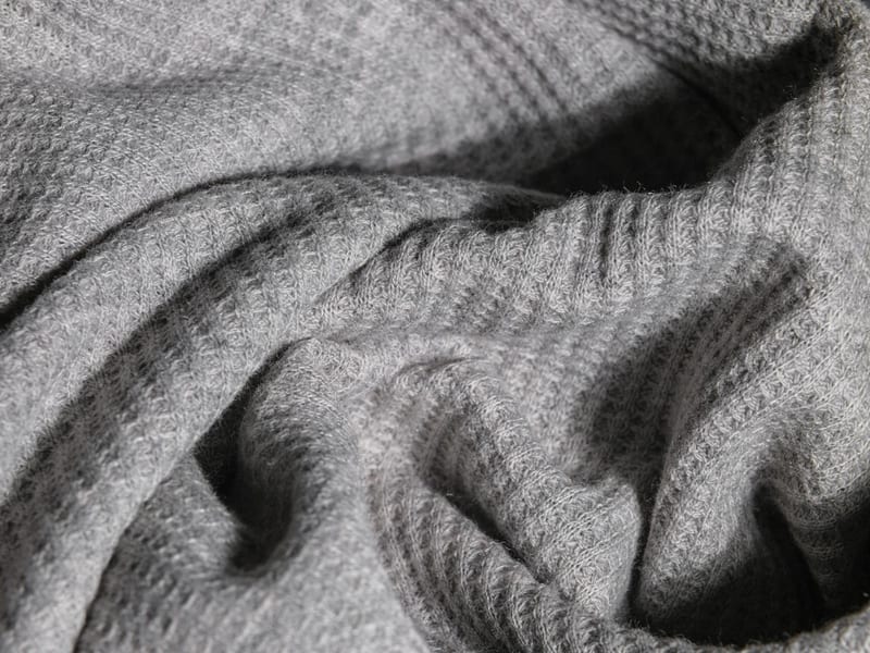 a close up of a gray blanket with a pattern on it