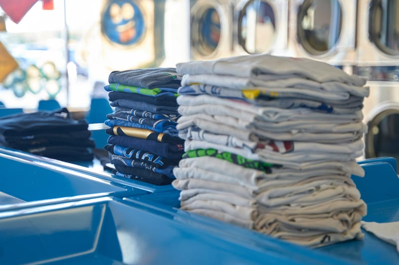 a stack of t-shirts in a laundromat with one that says ucla on it