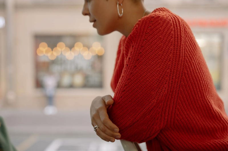 a woman in a red sweater is sitting at a table with her hands folded