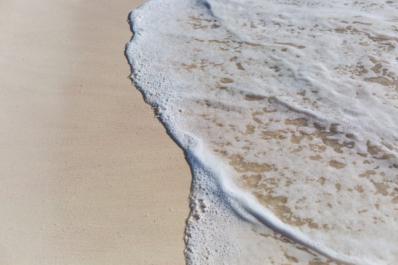 a wave is breaking on a sandy beach