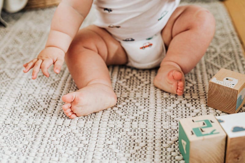 a baby is sitting on a rug next to wooden blocks with the letter f on them